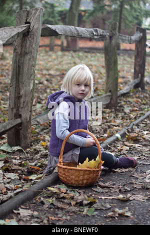 Giovani, bionda, bambini che giocano in foglie di autunno a Apley boschi, Shropshire Foto Stock