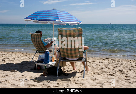 Due persone in relax sulla spiaggia Studland, Isle of Purbeck, Dorset, Regno Unito Foto Stock