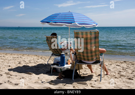 Giovane rilassante sulla spiaggia sabbiosa a Studland, Dorset, Regno Unito Foto Stock