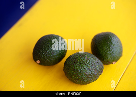 Frutto di avocado (Persea americana) su una tabella di colore giallo in Guatemala Foto Stock