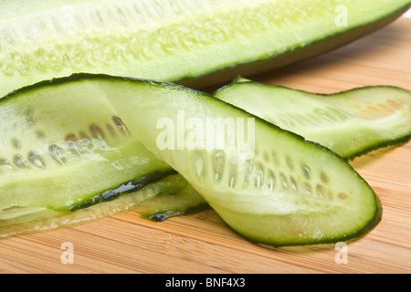 I nastri tagliati a fettine di cetriolo dal basso una prospettiva sul bambù in legno tagliere. Foto Stock