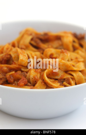 Autentica sana in italiano o in stile mediterraneo Tagliatelle alla bolognese Pasta servita in una ciotola con il n. di persone contro uno sfondo bianco Foto Stock