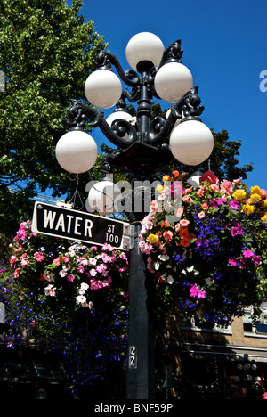Acqua Strada segno su un lampione con globo lampadina titolari cesti floreali pendenti Gastown Vancouver Foto Stock