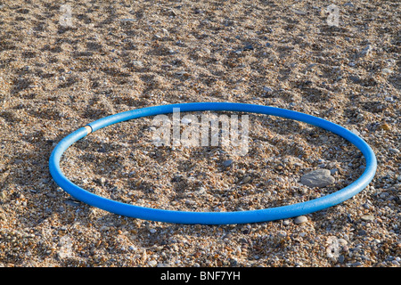 Blu anello in plastica su una spiaggia di ciottoli. Foto Stock