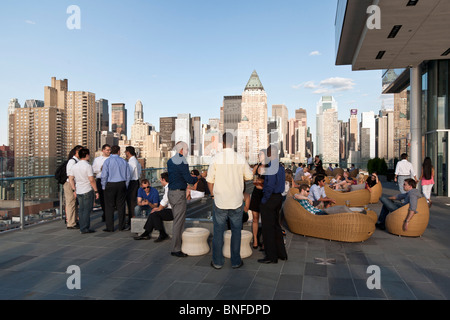 Diversi gruppi di giovani Newyorkesi socializzare bere e godere di splendida vista panoramica di Manhattan da inchiostro 48 Hotel Stampa bar sul tetto Foto Stock