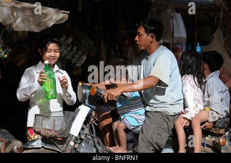 Padre di tre figli in moto l'acquisto di benzina, Cambogia Foto Stock