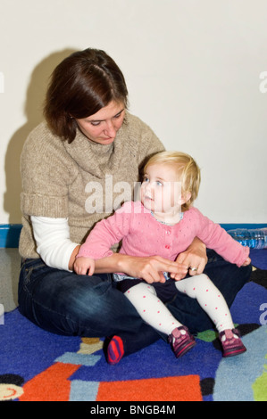 Ritratto verticale di una giovane mamma con la sua bimba in corrispondenza di un genitore e bambino "ing e segno' class, firma la parola papà. Foto Stock