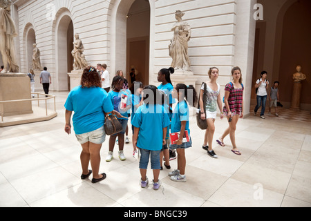 Un gruppo di studentesse che indossa identici blu brillante tee shirt in una gita in estate per il Metropolitan Museum of Art di New York City Foto Stock
