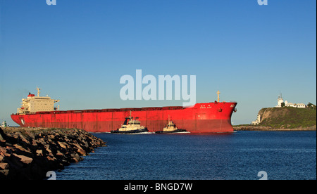 Nave da carico di entrare nel fiume del cacciatore sul suo modo al porto di Newcastle, NSW, Australia. Ci sono tre rimorchiatori assistere Foto Stock