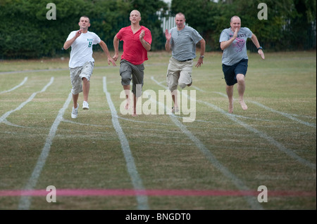 Papà competitiva sprint per la linea in gara i genitori alla fine di un tradizionale fine del termine scuola di sport al giorno Foto Stock