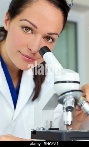 Una bellissima femmina o medico ricercatore scientifico con il suo microscopio in un laboratorio. Foto Stock