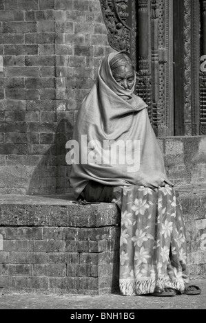 Vecchia donna in appoggio in Bhaktapur Square, Nepal Foto Stock