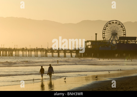 Matura per passeggiare sulla spiaggia vicino a Santa Monica Pier al tramonto Foto Stock