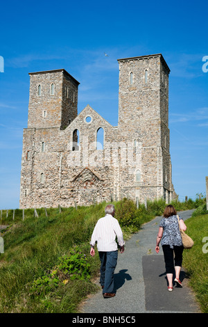 I turisti a piedi verso il castello di Reculver sul litorale di Kent. Due torri della chiesa di Santa Maria Foto Stock