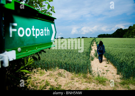 Il verde sentiero pubblico segno nella campagna di Kent, Donna che cammina sul sentiero Foto Stock