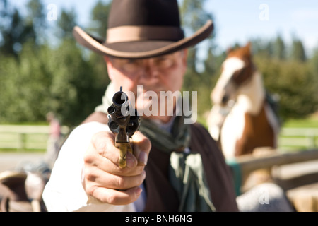 Cowboy pistola di puntamento, concentrarsi solo su gunpoint, cavallo in background Foto Stock