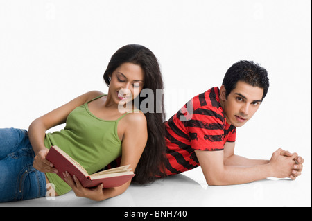 Donna appoggiato su di un uomo con la schiena e la lettura di un libro Foto Stock