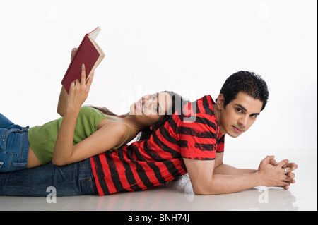 Donna sdraiata su un uomo della schiena e in possesso di un libro Foto Stock