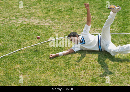 Cricket fielder immersioni subacquee per fermare una palla vicino alla linea di confine Foto Stock