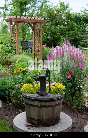 Un vecchio decorativo pompa acqua nel giardino con fiori in Reinland, Manitoba, Canada. Foto Stock