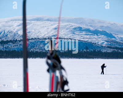 Uno sciatore fa il suo modo al di sopra del congelato lago Kaalasjärvi a Kiruna, Lapponia, Svezia settentrionale. Foto Stock