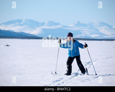 Un otto anni ragazza di sci si fa strada sopra il Kaalasjärvi congelati lago di fronte al massiccio del Kebnekaise a Kiruna. Foto Stock