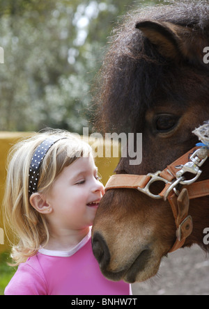 Bimba bionda adora il suo pony divertente ritratto Foto Stock