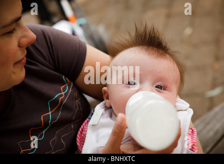 Giovane madre bottiglia alimenta il bambino. Foto Stock