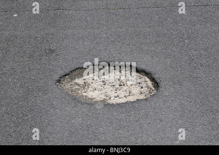 Buca in strada causato da una grave inverno meteo. Surrey, Inghilterra Foto Stock