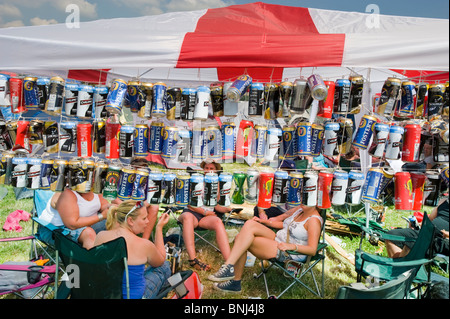 Glastonbury Festival 2010. Persone riparo sotto tenda con Inghilterra bandiera come un tetto con appeso utilizzato e vuoto di lattine di birra come una parete laterale. Foto Stock