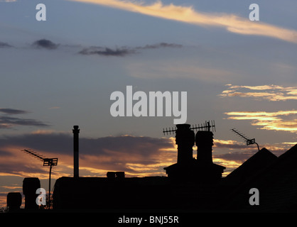 Sagome di camini e antenne contro il cielo al tramonto Foto Stock