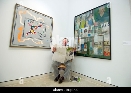 Una guardia a Pallant House Galleria d'arte, Chichester, West Sussex, legge il telegrafo di domenica di fronte a Peter Blake pittura Foto Stock