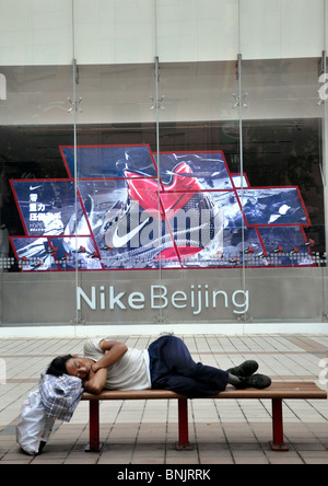 Senzatetto uomo dorme nella parte anteriore del negozio Nike a Pechino in Cina Foto Stock