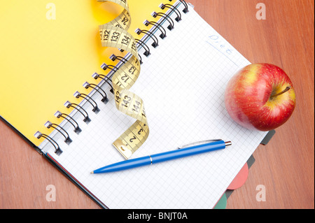 Pianificazione di una dieta. Un notebook c un iscrizione - la dieta, un nastro di misurazione, un apple e penna Foto Stock