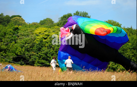 3 uomini lancio un enorme aquilone al Brighton Kite Festival evento estivo Sussex Regno Unito Regno Unito Foto Stock