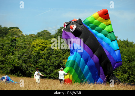 3 uomini lancio un enorme aquilone al Brighton Kite Festival evento estivo Sussex Regno Unito Regno Unito Foto Stock