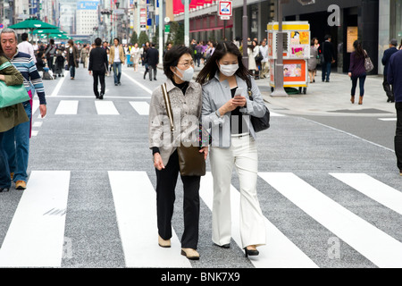 Le donne di protezione da indossare maschere viso in Chuo-dori a Ginza 4-chome, Tokyo, Giappone Foto Stock