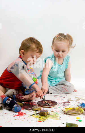 Ritratto di due bambini un ragazzo e una ragazza pittura insieme, migliori amici isolato su bianco Foto Stock