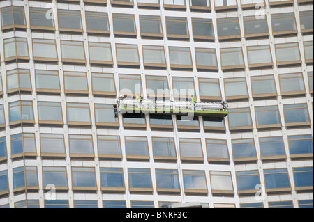 Detergenti per finestre su un gantry pulire il vetro di un centro della città edificio per uffici Foto Stock