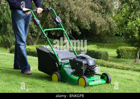 La falciatura di un giardino prato con John Deere falciatrice rotativa Foto Stock