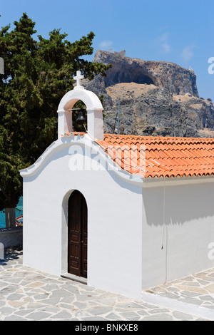 La cappella dipinta di bianco a St Paul Bay con l'acropoli dietro, Lindos, Rodi, Grecia Foto Stock