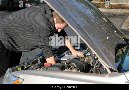 Uomo che ripara ripartiti in auto al di fuori in una giornata di sole. Foto Stock