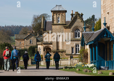 Escursionisti a piedi attraverso il villaggio di Edensor sul Chatsworth Estate, il Parco Nazionale di Peak District, Derbyshire. Foto Stock