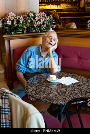 Uomo anziano sonnecchiare seduti a un tavolo in un Cafè Italiano Foto Stock