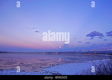 Tramonto su Cook Inlet con luna piena visibile, Anchorage, SC, AK, inverno Foto Stock