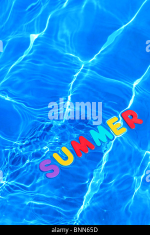La parola estate fatta da lettere di schiuma galleggiante sulla superficie dell'acqua di piscina Foto Stock