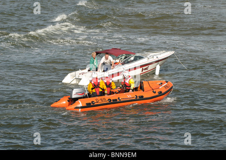 Costiera RNLI barca di salvataggio del controllo di coppia su off powerboat Burry Port, Carmarthenshire South Wales UK Foto Stock