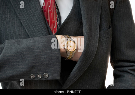Upperclass uomo raggiungendo in tasca per il libretto degli assegni con orologio d'oro Foto Stock