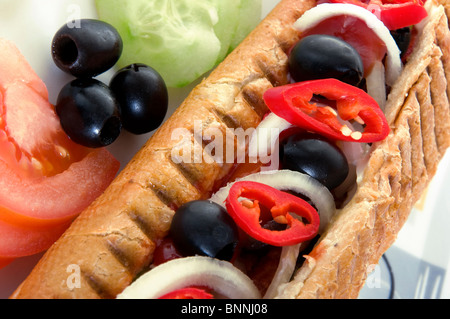 Close-up di hot dog con verdure. Il fast food, pomodoro, peperoncino, cipolla, salsiccia, grigliate di rotolo, olive, cetriolo Foto Stock
