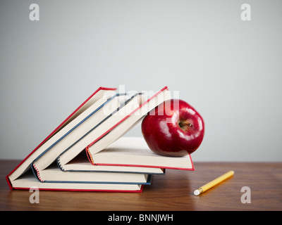 Pila di libri e mela rossa sulla scrivania. Spazio di copia Foto Stock